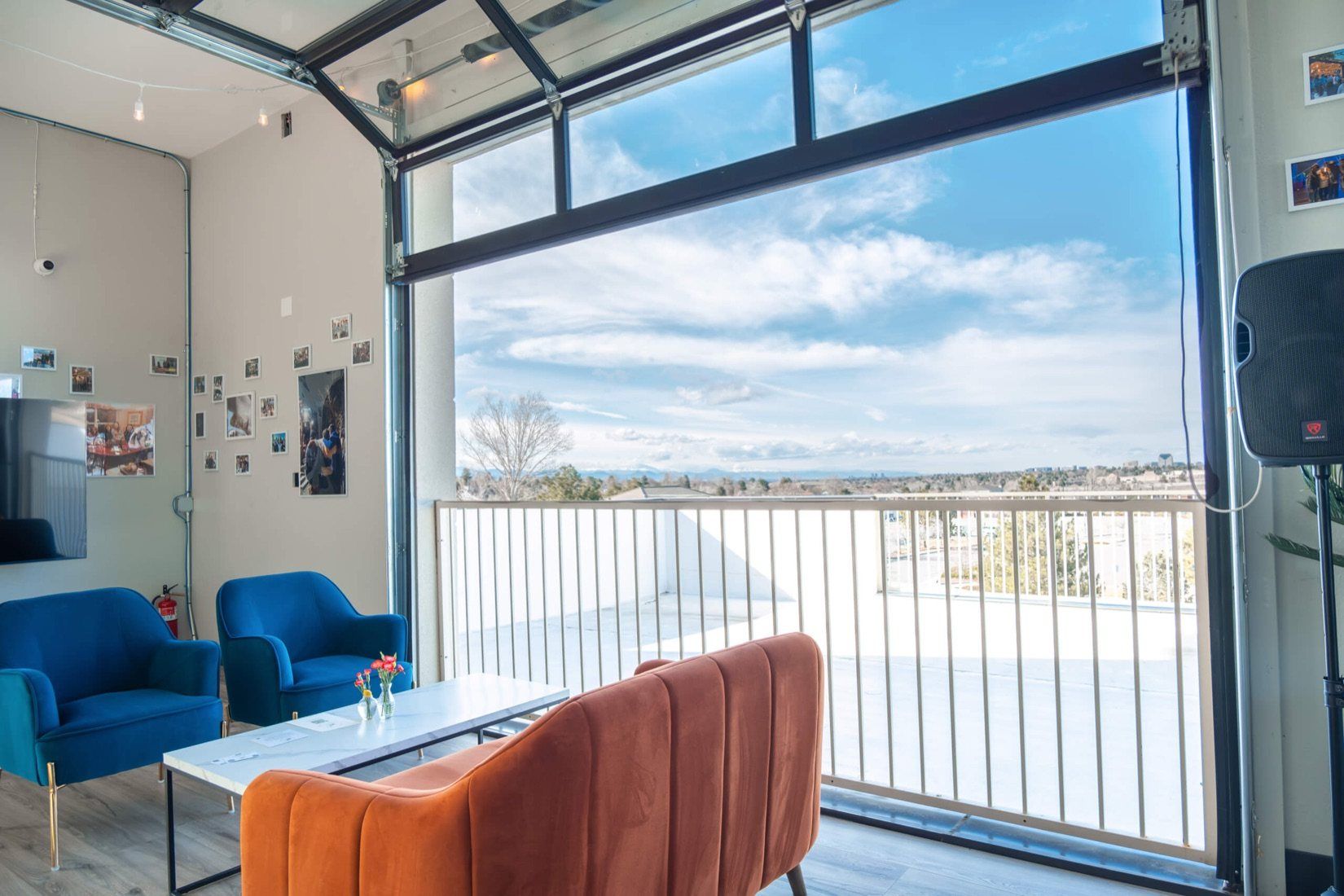 The room upstairs at Happy Crew Coffee House: blue armchairs, an orange couch and a glass garage door open to the Front Range