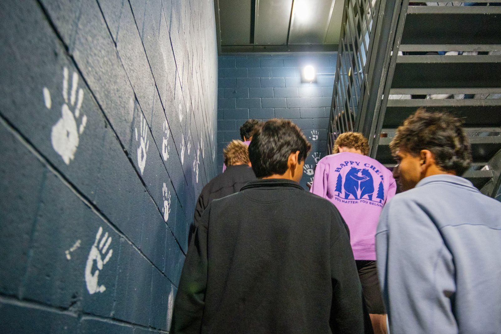 Teens heading up the stairs past the handprint wall