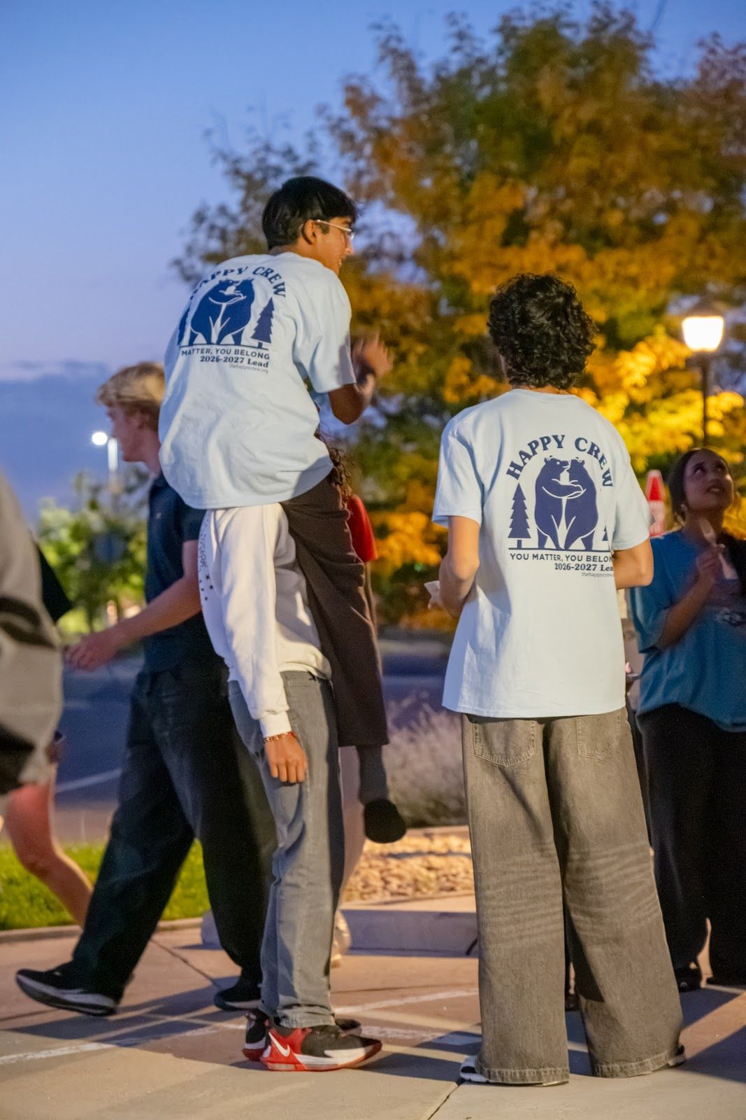 Teens in Happy Crew tees walking in at dusk