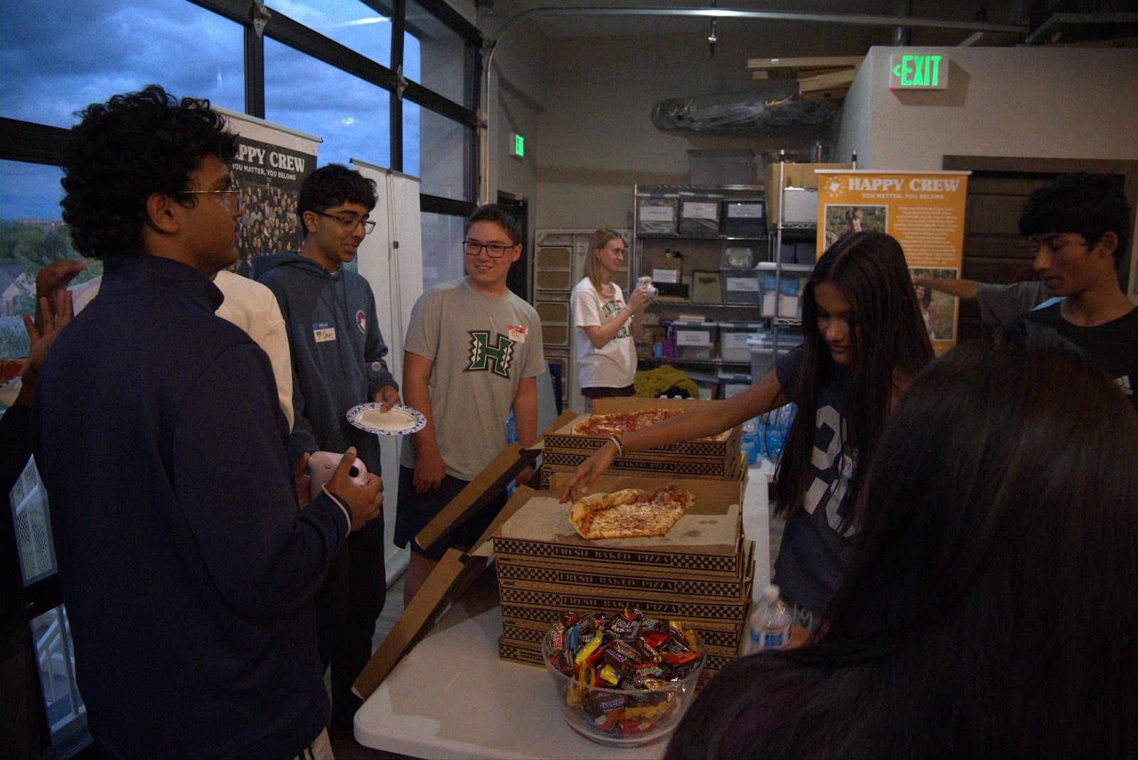 Teens in the dinner line, pizza on the table